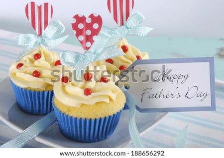 Happy Fathers Day bright and cheery red white and blue decorated cupcakes with heart toppers and gift tag on vintage blue shabby chic background.