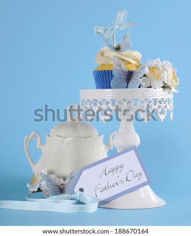 Happy Fathers Day blue butterfly theme cupcake on white cupcake stand with greeting gift tag against a blue background.