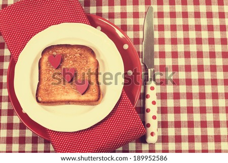 Retro vintage style red check table setting with polka dot plate and knife and toast with hearts for Mothers Day, romantic or Valentine breakfast.