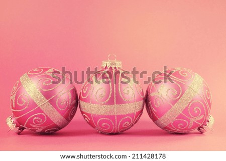 Beautiful fuchsia pink festive bauble ornaments on a feminine pink background with copy space for Merry Christmas or Happy Holidays seasons greetings, with retro vintage filter.