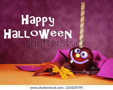 Happy smiling crazy face red toffee apple candy for trick or treat Halloween food against a bright dark pink red and orange background, with sample text.