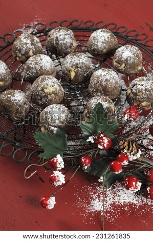 Christmas chocolate and caramel fudge cookies on vintage baking rack on dark red rustic wood background with festive decorations. Vertical closeup.