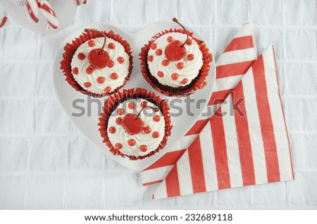 Christmas holiday dessert party food with red and white theme red velvet, cream and cherry cupcakes.