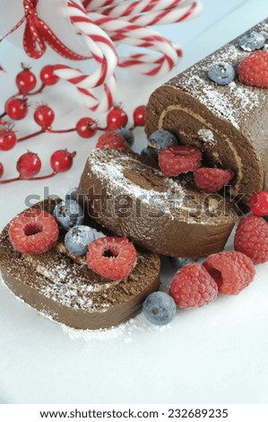 Christmas holiday chocolate roulade yule log swiss roll with berries dessert party food - closeup vertical.