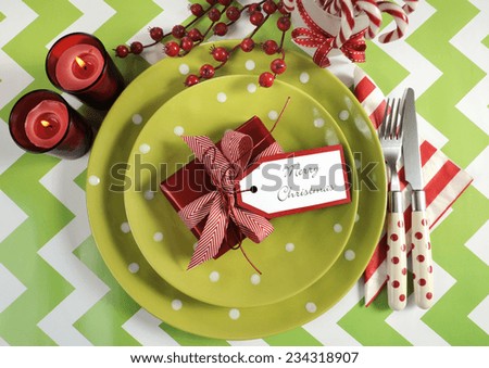 Bright colorful modern Christmas children family party table place settings in lime green, red and white theme on a chevron stripe table. Overhead.