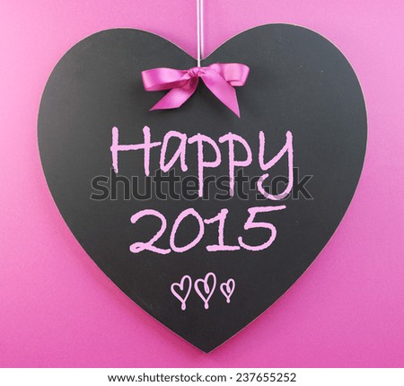 Happy New Year greeting for 2015 message on heart shape blackboard against a pink background.