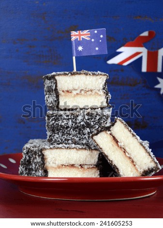 Happy Australia Day January 26 party food with iconic Australian lamington cakes on dark red and blue vintage rustic recycled wood background.