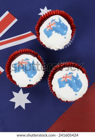 Happy Australia Day January 26 party food with red velvet cupcakes and Australian maps rice paper toppers on dark red and blue vintage rustic recycled wood background.