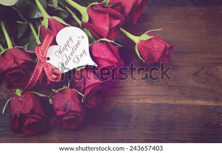 Vintage red roses gift for Valentines Day, birthday or special occasion on recycled distressed natural dark wood background.