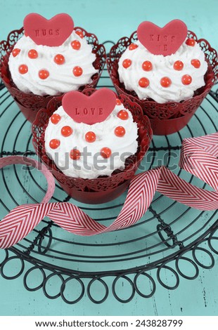 Happy Valentine red velvet cupcakes with love messages on vintage baking rack on green teal blue sixties style vintage wood background.