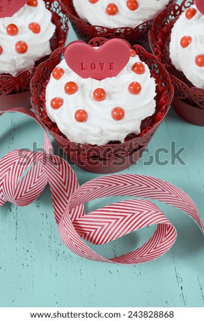 Happy Valentine red velvet cupcakes with love messages on green teal blue sixties style vintage wood background.