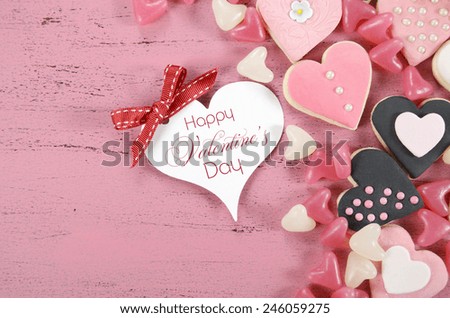 Pink, black and white homemade heart shape cookies on vintage shabby chic pink wood background with Happy Valentines Day greeting gift tag and sample text.