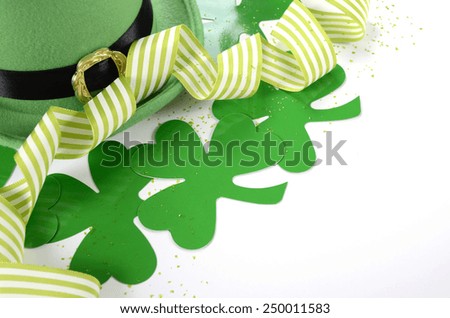 Happy St Patricks Day leprechaun hat with shamrocks and party ribbons on white table.