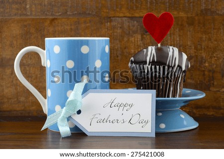 Happy Fathers Gift with cupcake and  blue and white polka dot coffee mug on wood background.