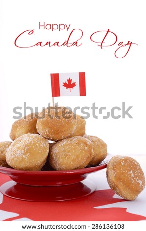 Stack of donut holes on red plate on Canadian maple leaf flag for Happy Canada Day celebration party.