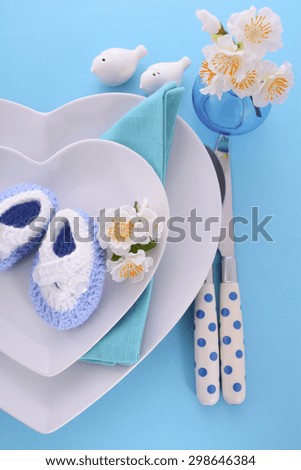 Its a Boy blue theme baby shower table place setting with heart shape plates on blue table background.
