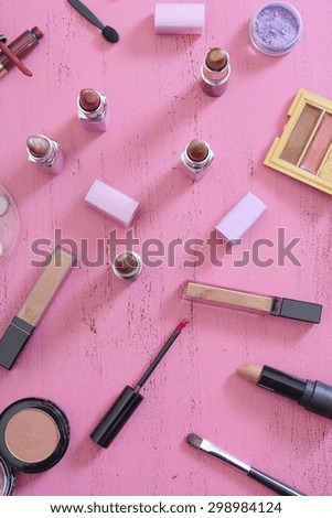 Early morning makeup routine and products on vintage shabby chic pink wood table.