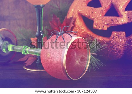Happy Halloween table with Jack O Lantern pumpkin with party wine goblets on rustic dark wood vintage background with added vintage style filters.