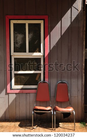 Windows of old, wooden cottage in the countryside with steal chair