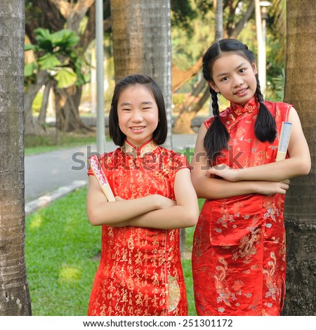 Asia female teenagers wear red suit pose for take photo in garden, Chinese New Year traditions