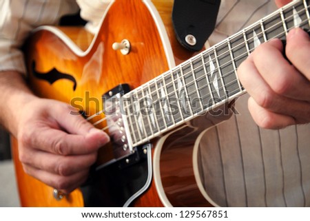 Closeup cropped view of the hands of a man playing a wooden guitar strumming a tune on the strings
