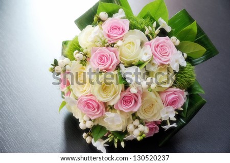Pretty fresh pink and white bridal bouquet with roses on a bed of foliage and leaves