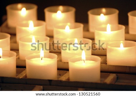 Group of small light burning candles casting a spiritual glowing light in a church or celebration