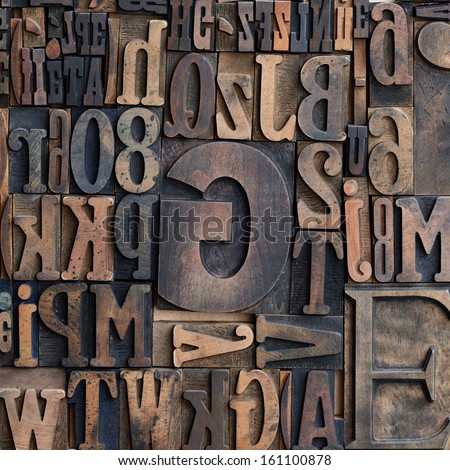 Jumbled arrangement of different sized wooden printers typeface letters of the alphabet forming a background pattern