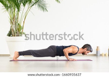Fit man doing Yoga chaturanga push-ups during his workout in a high key gym with potted palm in a low angle side view in a health and fitness concept Foto stock © 