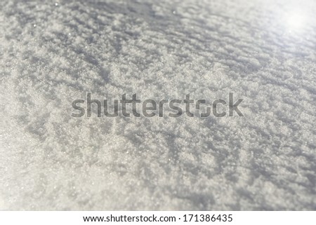 Sun flare on a snow background texture in low angle light