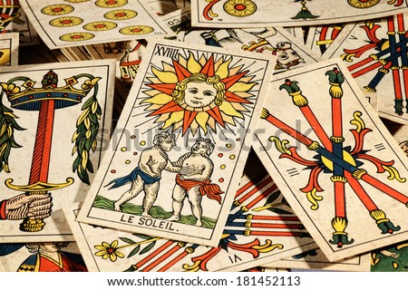 Set of old tarot cards lying in a scattered heap with their designs uppermost and a picture of the sun on top