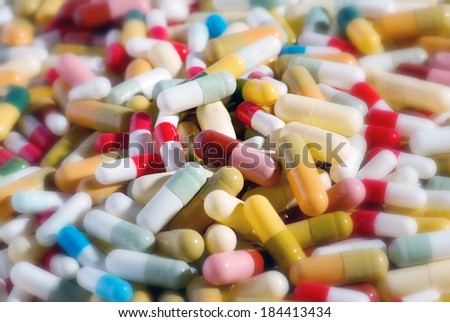 Background of assorted pharmaceutical capsules and medication in different colors denoting different drugs and antibiotics in a health care concept