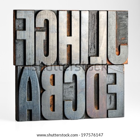 Alphabet letters on old metal printers blocks for setting type arranged so that the letters are facing to the left with an incomplete set A through J plus L