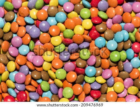 Background texture of brightly colored round sweets or sugar coated glazed candy in the colors of the rainbow