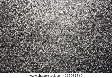 Background texture of a shiny metal sheet with a rough stippled textured surface reflecting light