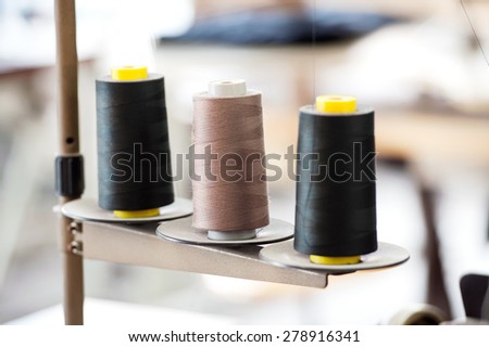 Three Industrial Spools of Thread in Black and Tan Colors in a Row in Manufacturing Setting