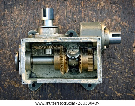 Opened old metal case on wooden board showing mechanism and gears
