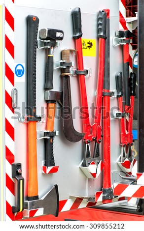 Collection of fire fighting tools and equipment neatly mounted on a metal panel on a fire engine or fire fighter\'s vehicle ready for emergency use