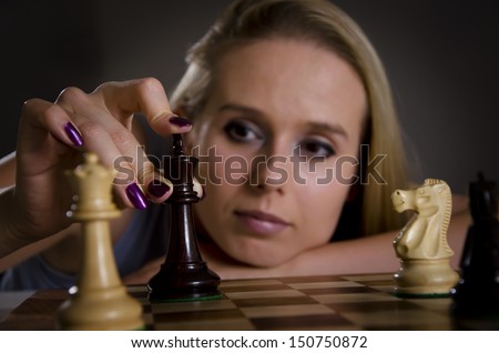 woman playing chess making her move with focus on the chess piece
