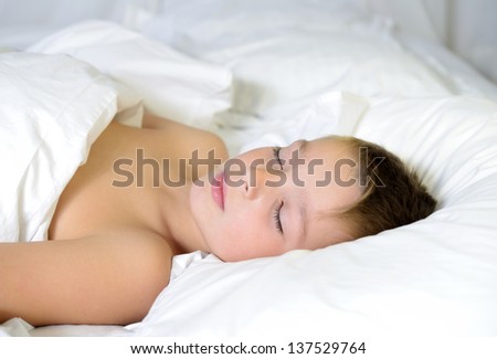 Adorable boy is sleeping in a bed