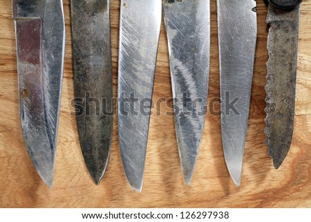 old knife blades on wooden background