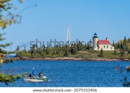 Copper Harbor Lighthouse on Lake Superior, with defocused fishermen in a boat Foto d'archivio © 