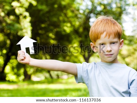 red-haired boy with a small house in hands on nature