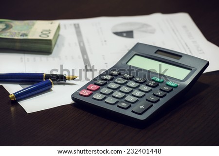 Business office desk with pen calculator charts and money