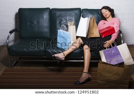 Tired woman lying on sofa with many shopping bags