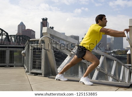 Male jogger stretching in city