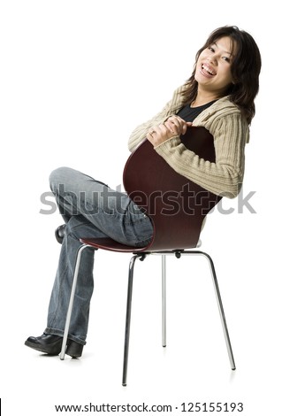 Full length of a young woman sitting on chair and turning back