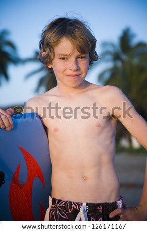 Portrait of young boy holding boogie board on the beach