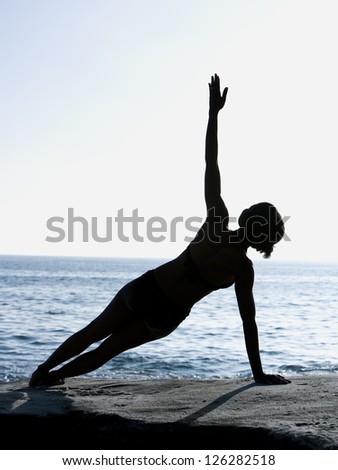 Silhouette of woman exercising on seashore