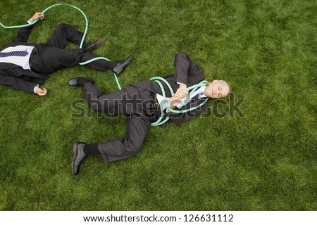 Business men wrapped in garden hose